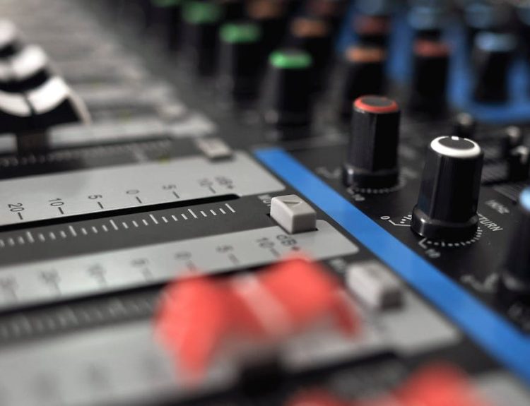 Detailed close-up of an audio mixing console with colorful knobs and sliders.