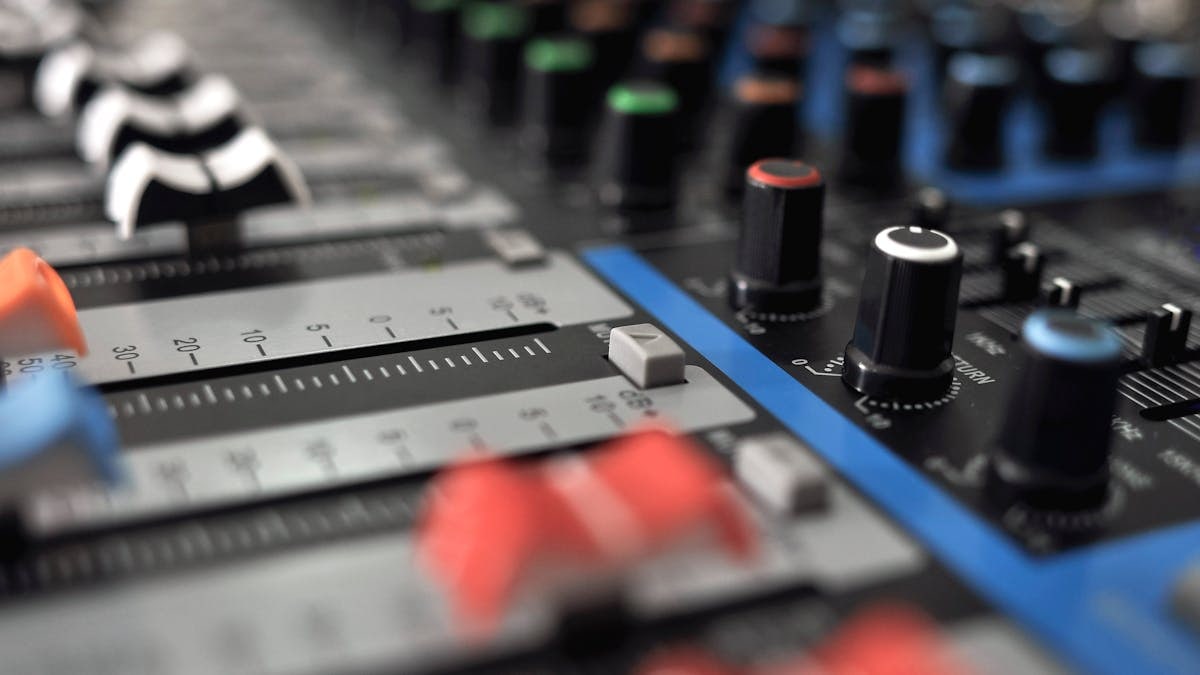 Detailed close-up of an audio mixing console with colorful knobs and sliders.