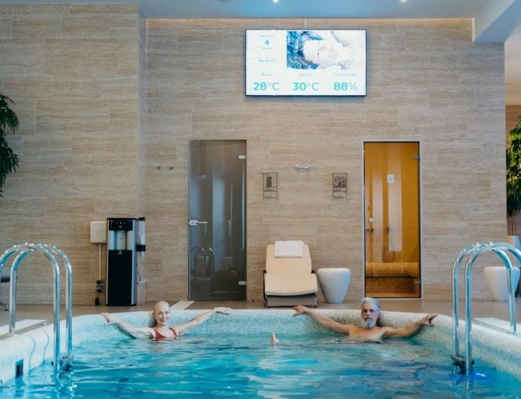 Two adults enjoying leisure time at an indoor swimming pool with spa-like ambiance.